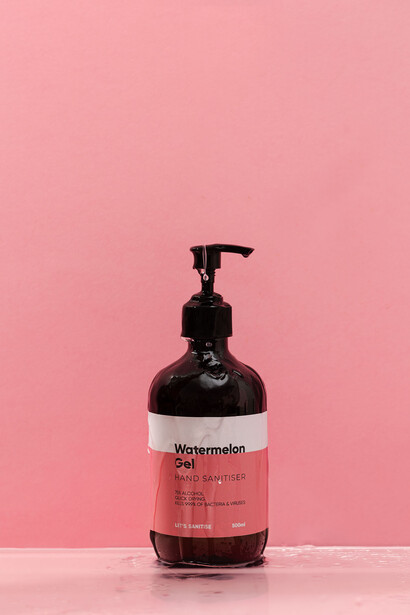 Dark glass pump bottle with white label on pink background.