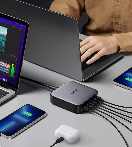 Multi-device charging setup with a central power hub connected to laptop, smartphones, and wireless earbuds.
