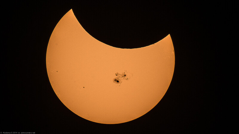 Partial solar eclipse showing the moon crossing in front of the sun with visible sunspots.