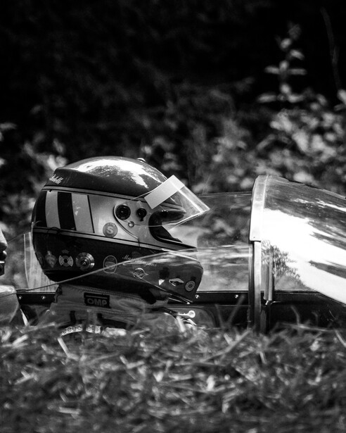 A racing driver suited up in modern equipment yet a retro helmet livery awaits instruction before driving his classic Ferrari up the infamous Goodwood hillclimb at the 2022 festival of speed.
