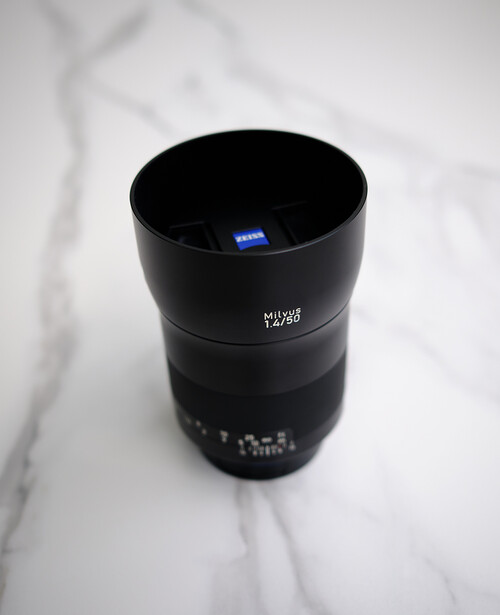 Black telephoto lens with aperture markings displayed on marble surface.
