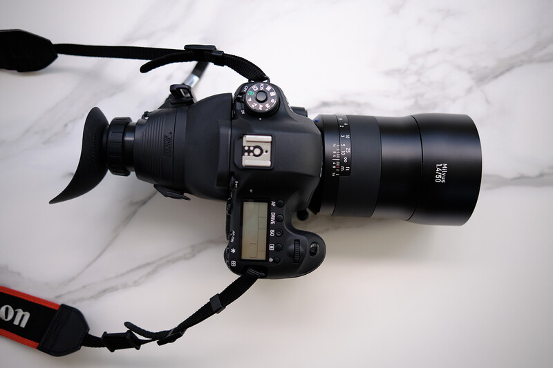 Canon cinema camera with attached lens, external monitor, and microphone mounted on marble surface.