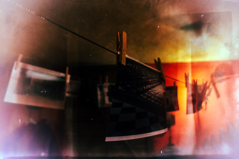 Clothesline with hanging photographs silhouetted against warm golden and orange light.