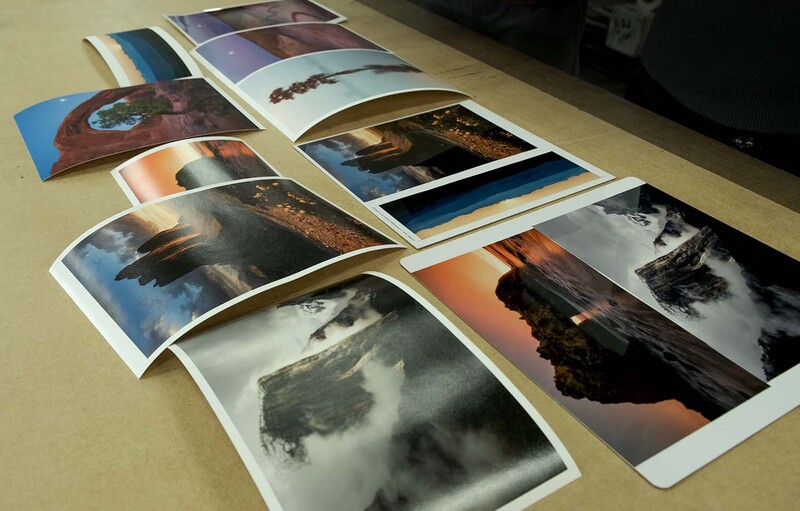 Printed landscape photographs arranged in overlapping rows on a tan surface.
