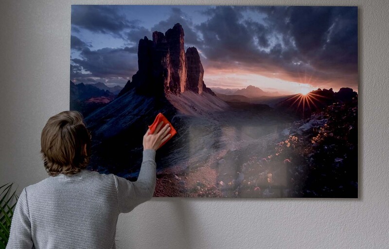 Person touching a large landscape photograph of dramatic rock formations at sunset.