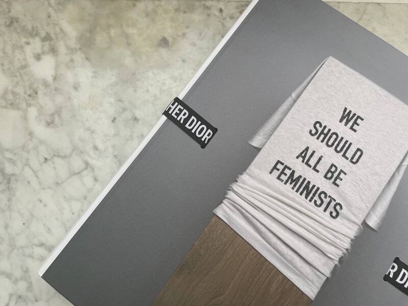 Styled flat lay of feminist books and typography on gray and marble surfaces.