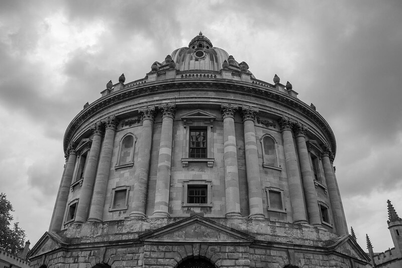 Circular neoclassical building with columned rotunda photographed from below against dramatic cloudy sky.