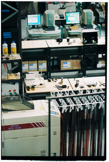 Professional photography lab setup with vintage equipment and film processing materials on multiple shelves.