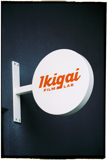 Illuminated signage for Ikigai Film Lab mounted on a dark textured wall.