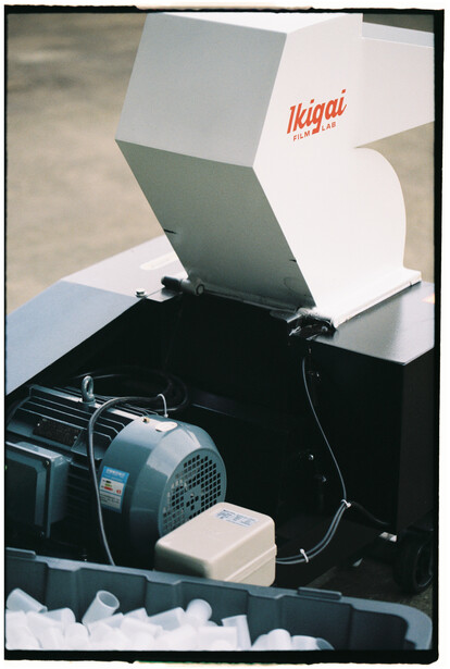 Ice maker or snow machine with motor and white reflector panel mounted on black base.