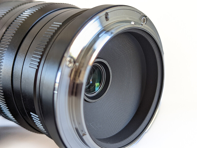 Close-up of a camera lens showing internal glass elements and helicoid focusing mechanism.
