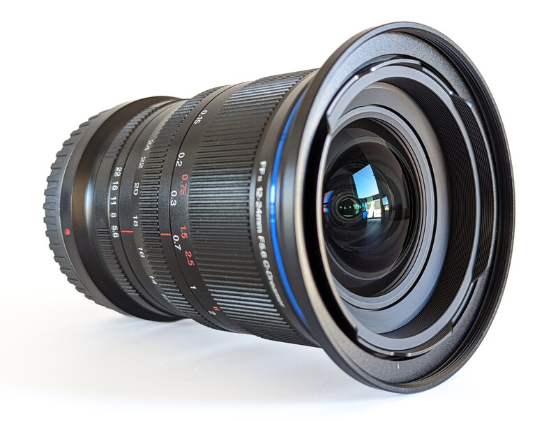 Wide-angle zoom lens with blue accent ring and visible glass elements, mounted at an angle against white background.
