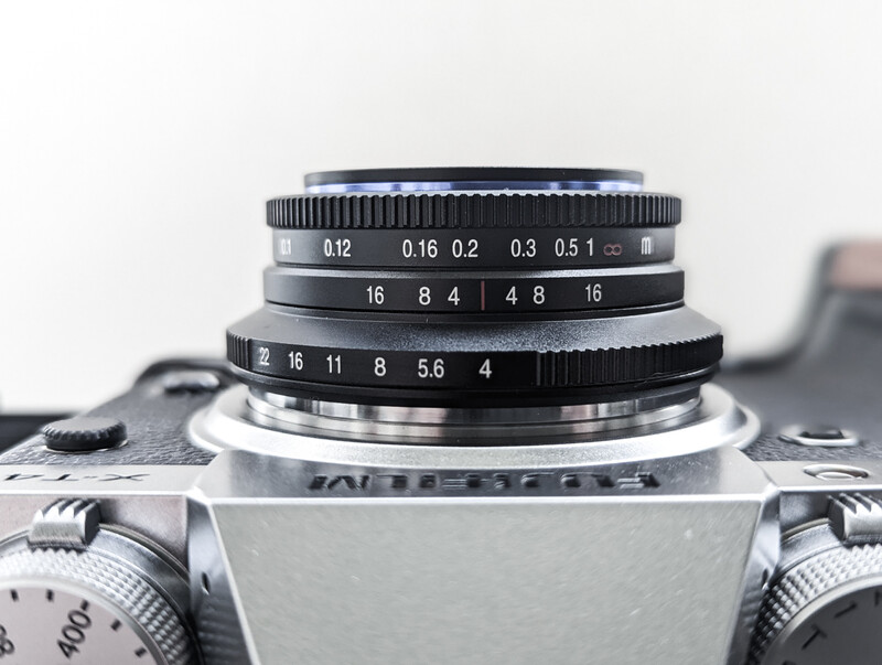 Vintage rangefinder camera with stacked lens elements showing depth markings and aperture scales.