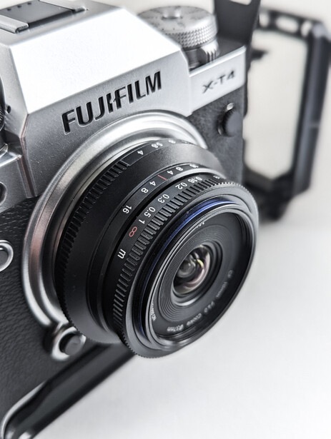 Fujifilm X-T4 mirrorless camera with prime lens mounted, displayed against white background.