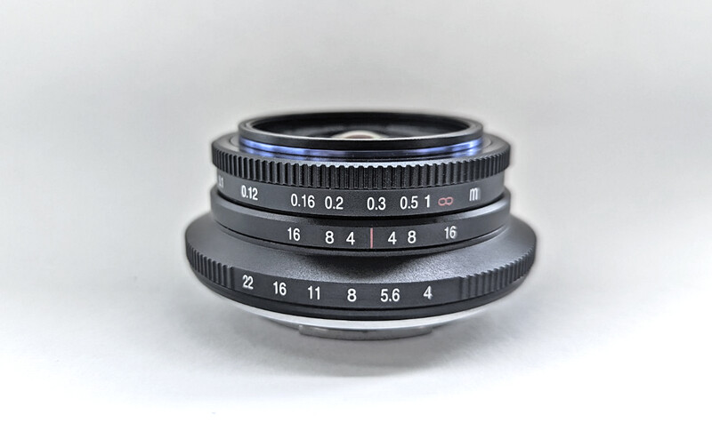 Vintage rangefinder lens with stacked optical elements and manual aperture and focus rings.