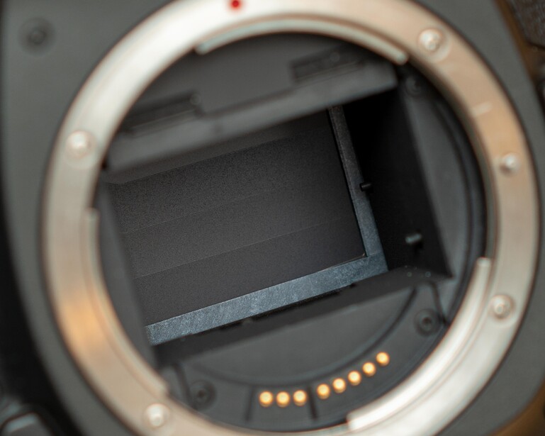 Camera mirror box interior with sensor contacts visible and shutter mechanism.