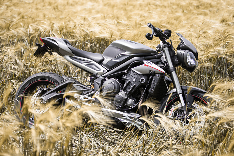 Dark motorcycle positioned in a golden wheat field during daytime.