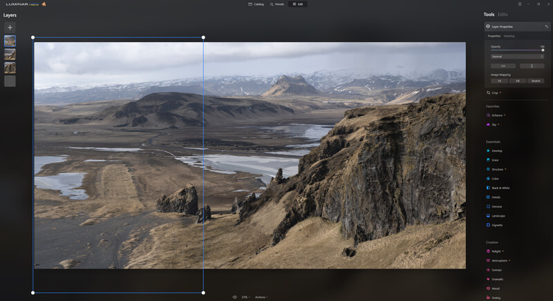 Icelandic landscape with volcanic terrain, glacial rivers, and distant snow-capped mountains viewed from a rocky cliff.