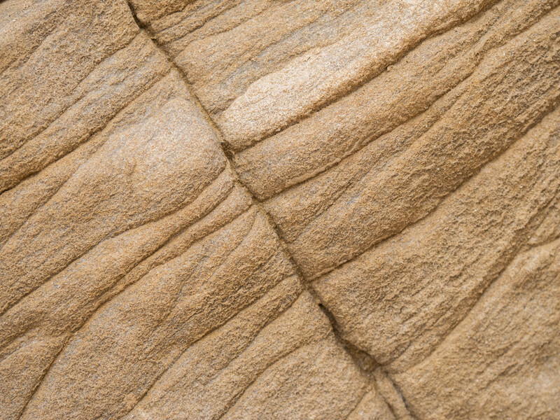 Close-up texture of layered sandstone with natural striations and weathered surface patterns.