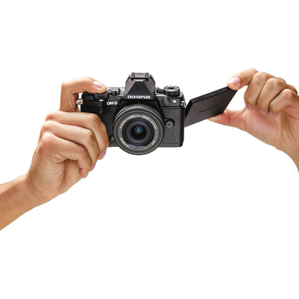 Hands holding a black DSLR camera with lens extended toward the viewer.