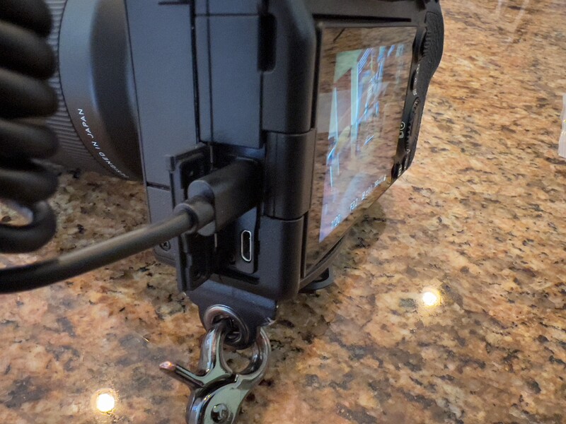Close-up of a camera mounted on a tripod head with a USB cable connected to its port.