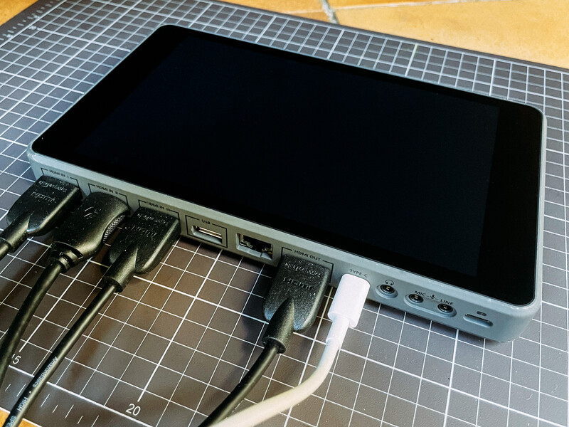 Tablet with black screen displaying on desk with cables and cutting mat in background.