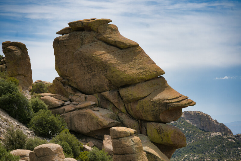 Stacked granite boulders forming a profile-like rock formation against a blue sky.
