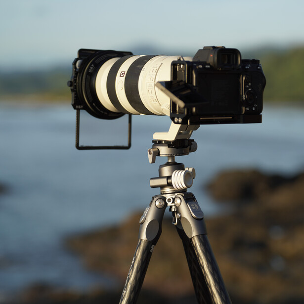 Professional telephoto lens mounted on tripod with mirrorless camera and gimbal head.