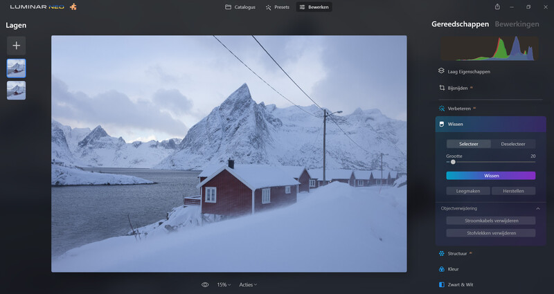 Snow-covered mountains rise behind red cabins on a frozen fjord at twilight.