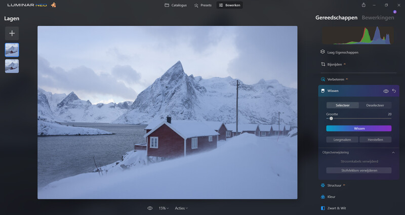 Red cabin beside a snow-covered fjord with jagged mountain peaks in the background under overcast sky.