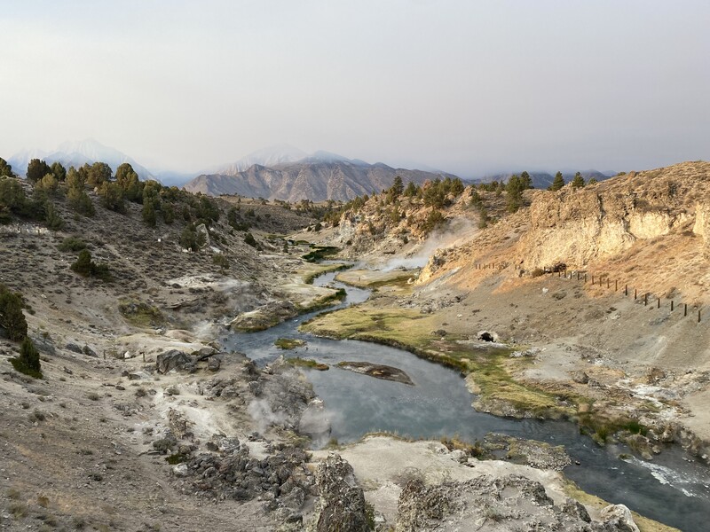 Geothermal landscape with hot springs, mineral pools, and steam vents amid volcanic terrain.