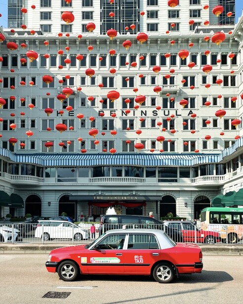 Red sedan parked in front of a multi-story apartment building decorated with red lanterns.