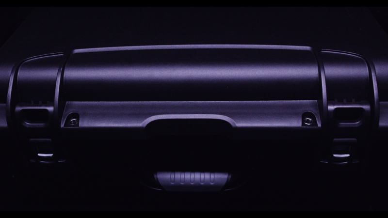 Rear view of a vehicle tailgate illuminated by dramatic side lighting against a dark background.