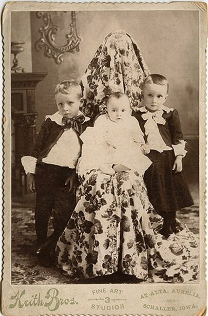 Victorian-era carte de visite showing a woman with lace veil and three young children in formal dark clothing.