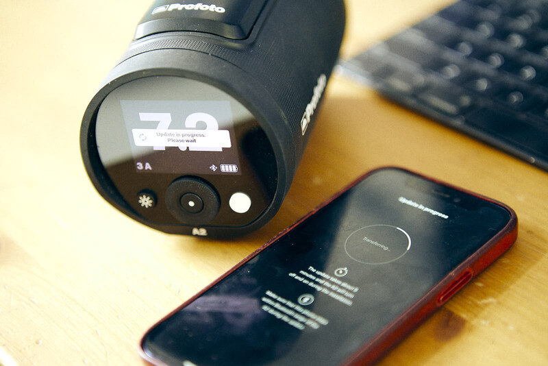 Thermal imaging camera with smartphone displaying live thermal data on wooden desk.