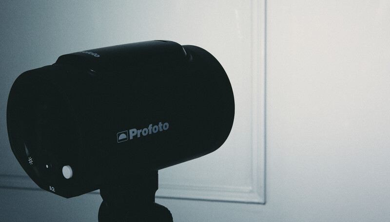 Profoto studio flash head mounted on a light stand in a studio environment.