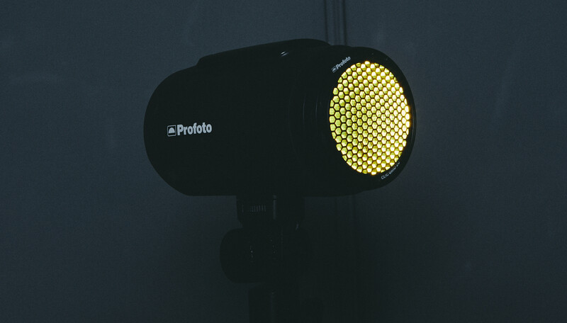 Profoto lighting unit with illuminated honeycomb grid on dark background.