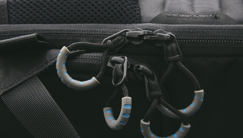 Climbing carabiners and harness gear with gray and blue accents coiled in a black equipment bag.