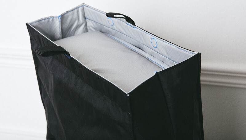 Black fabric laundry hamper with white mesh interior and carrying handles.
