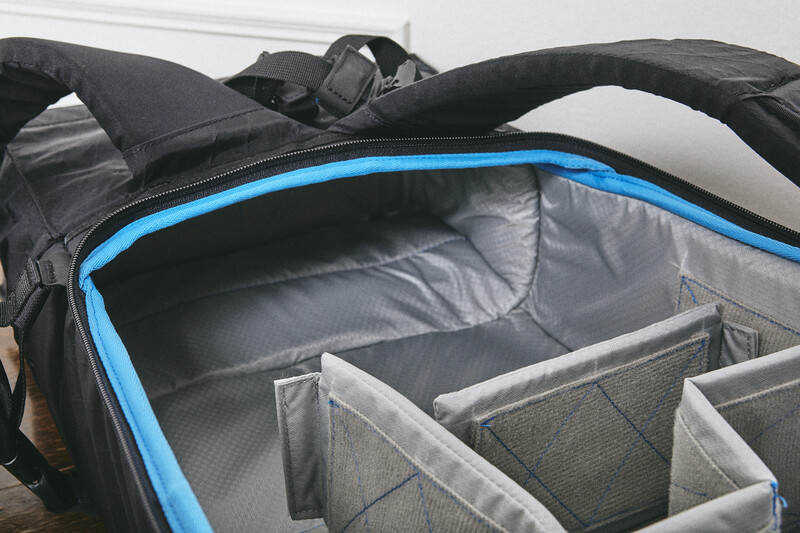 Open camera backpack with blue trim showing gray fabric dividers and compartments inside.