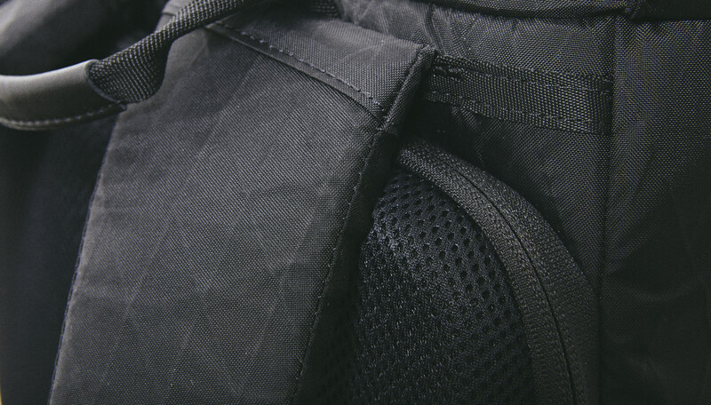 Close-up detail of fabric textures on a dark backpack or gear bag showing canvas and mesh panels.