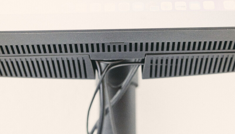 Underside view of a flat-panel monitor mounted on a pole stand, showing cable management and ventilation grilles.