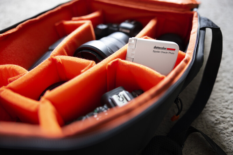 Orange-lined camera bag with organized compartments holding lenses and photography accessories.