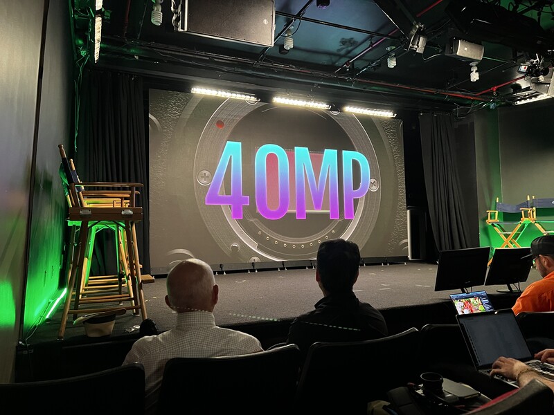 Stage setup with neon 4QMP text display and professional lighting rig overhead.