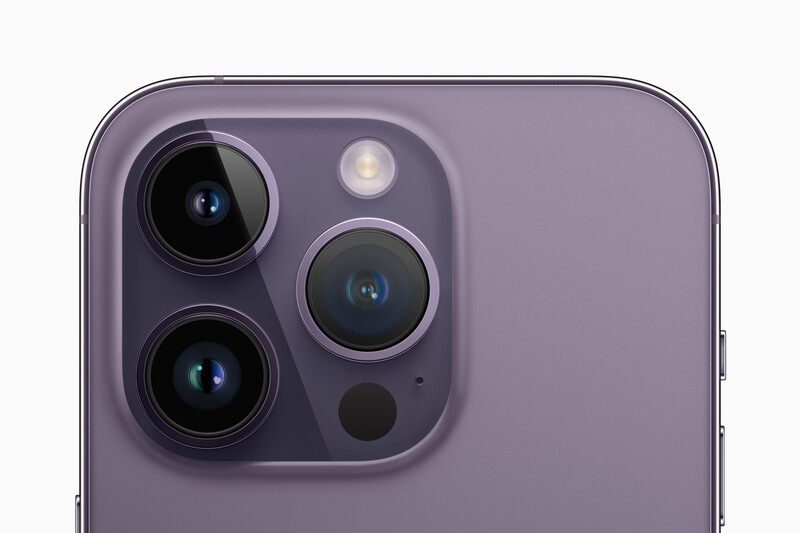 Close-up of a smartphone's rear camera module with three lenses and a flash unit on a purple background.