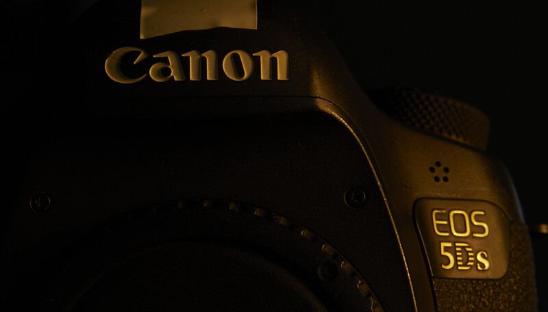 Canon EOS 5D Mark S DSLR camera photographed against a dark background with warm golden lighting.