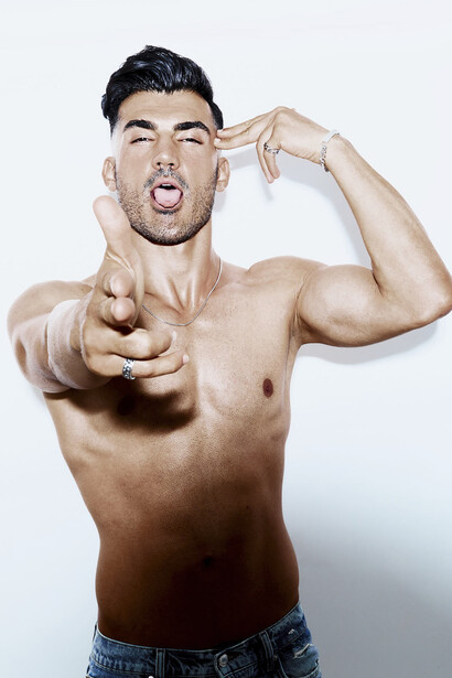 Shirtless man with muscular build pointing at camera with playful expression.