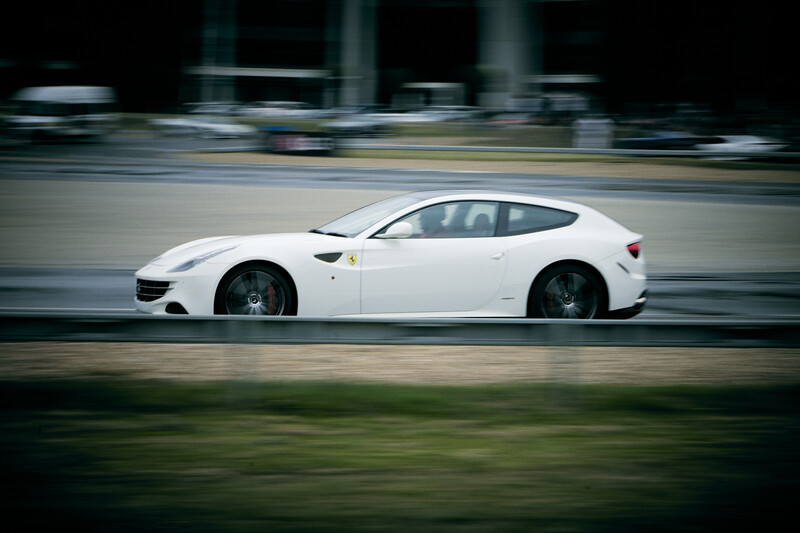 White sports car in motion blur, shot from the side on a city street.