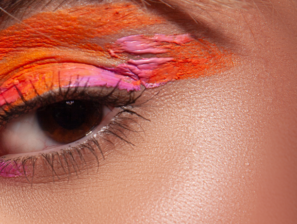 Close-up of eye makeup featuring vibrant orange and pink eyeshadow with precise blending.