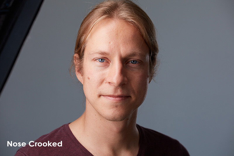 Portrait of a person with a slightly crooked nose against a neutral gray background.